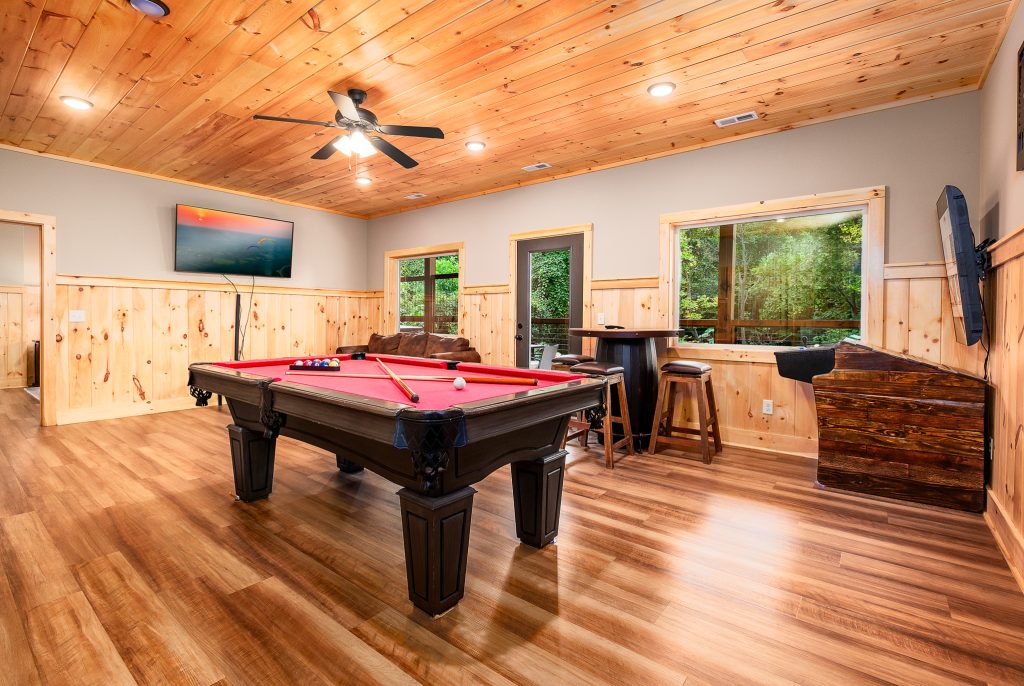 Wood-paneled game room with red pool table at a vacation rental in the Smoky Mountains.