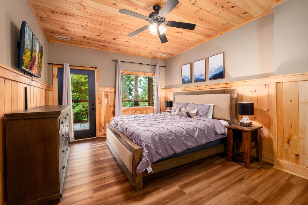 Wood-paneled king bedroom with balcony doors at a vacation rental in the Smoky Mountains.