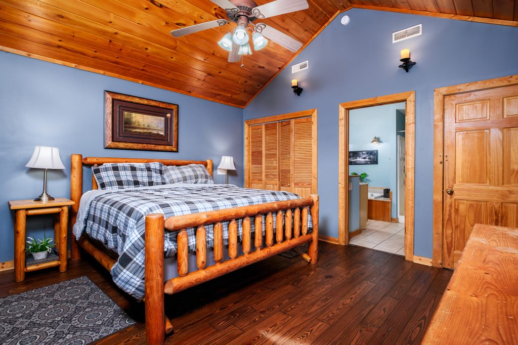 Log cabin bedroom with blue accent wall at a vacation rental in the Smoky Mountains.