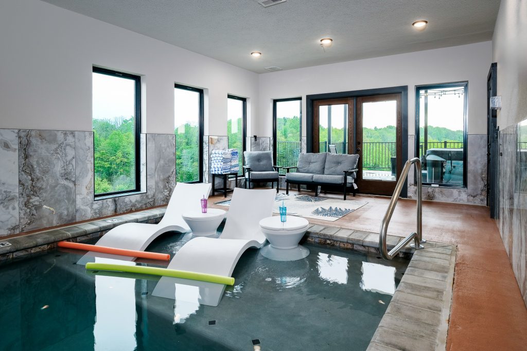 Indoor pool with windows and lounge seating at a vacation rental in Sevierville, Tennessee.