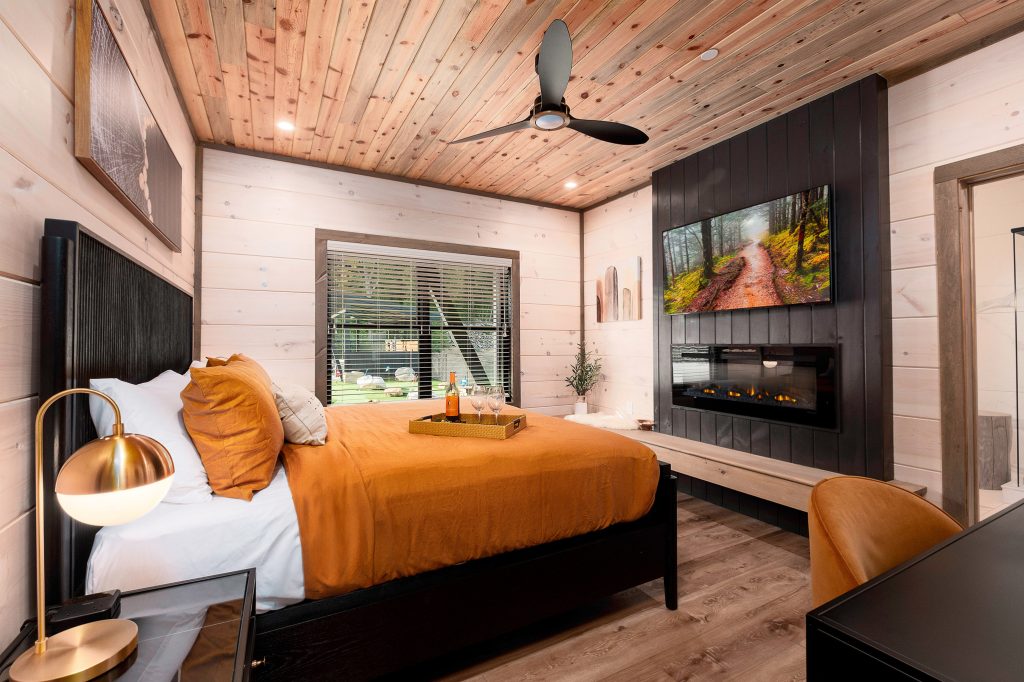 Orange-accent king bedroom with fireplace at a vacation rental in Wears Valley in the Smoky Mountains.