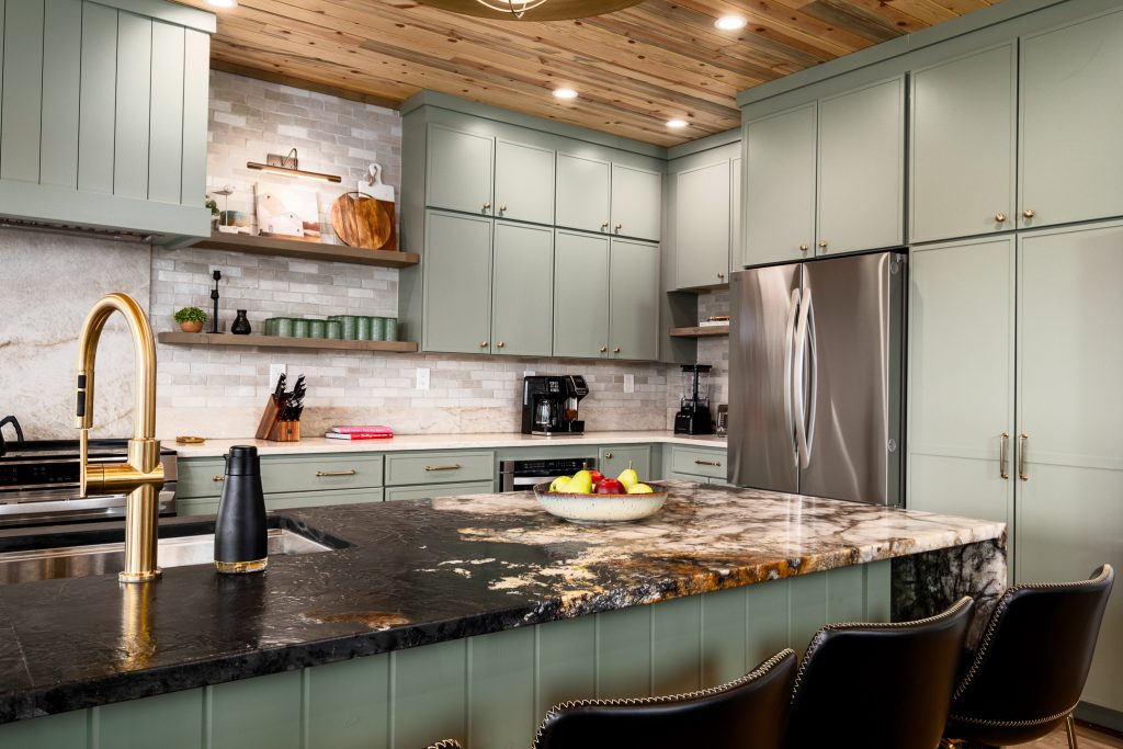 Sage-green cabin kitchen with a granite island and warm wood ceiling in Wears Valley.