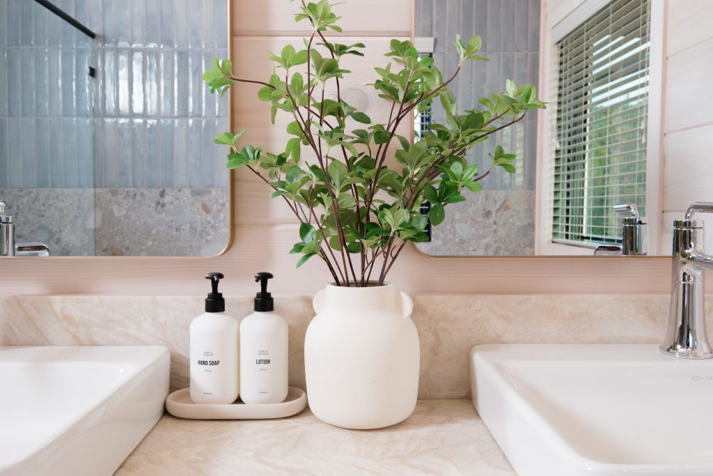 Spa-style bathroom vanity with twin vessel sinks and greenery between them.