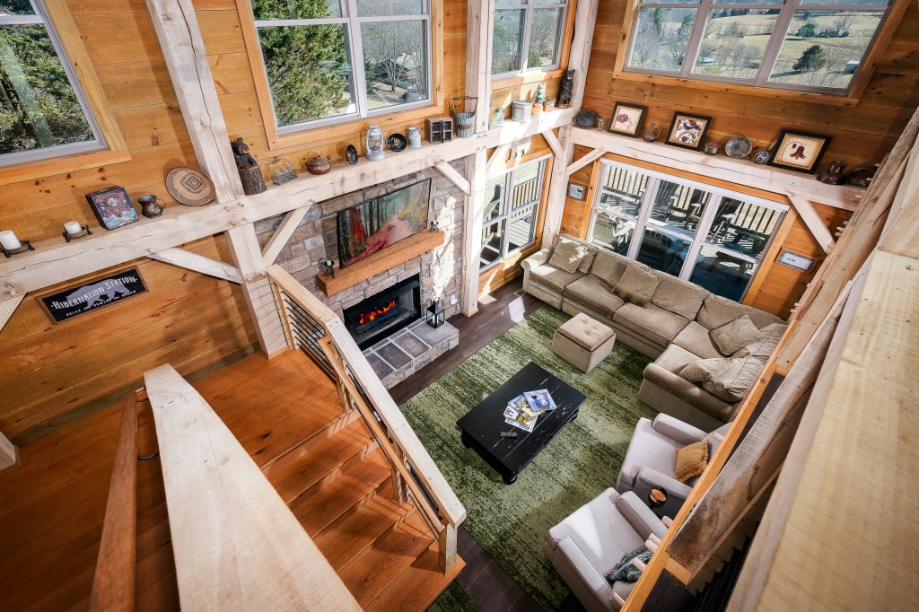 Second loft angle overlooking the sectional, fireplace, and open timber structure.