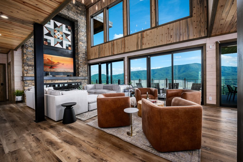 Double-height living room with leather chairs facing a stone fireplace in Wears Valley.