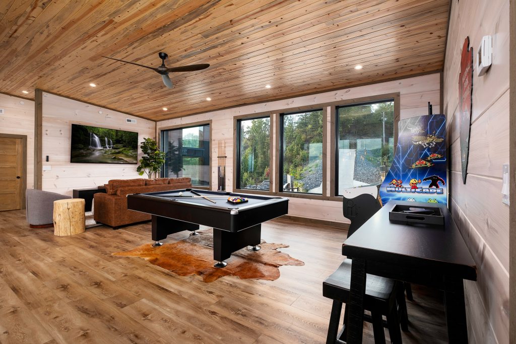 Pool table and arcade beside picture windows at a vacation rental in Pigeon Forge, Tennessee.