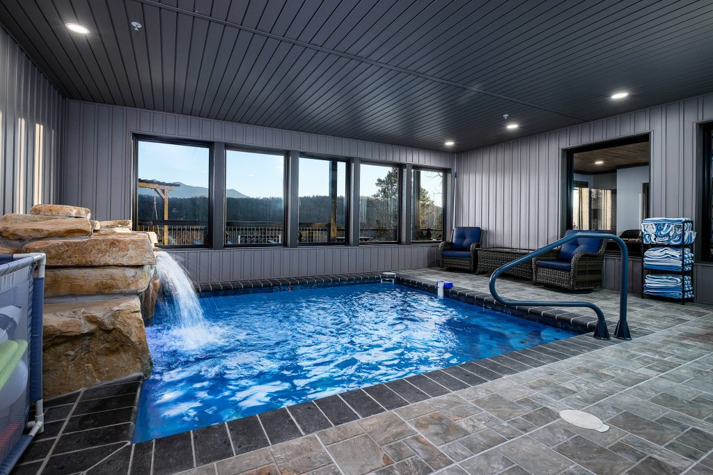 Indoor pool with waterfall and mountain windows at a vacation rental in Gatlinburg, Tennessee.