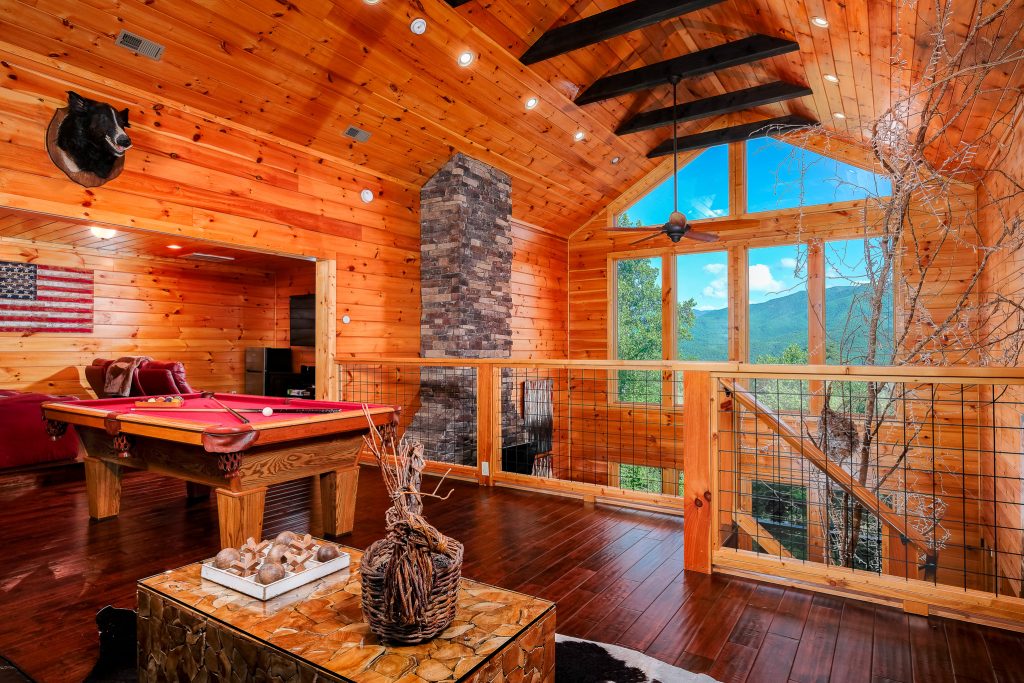 Loft pool table beside stone chimney at a vacation rental in Gatlinburg, Tennessee.