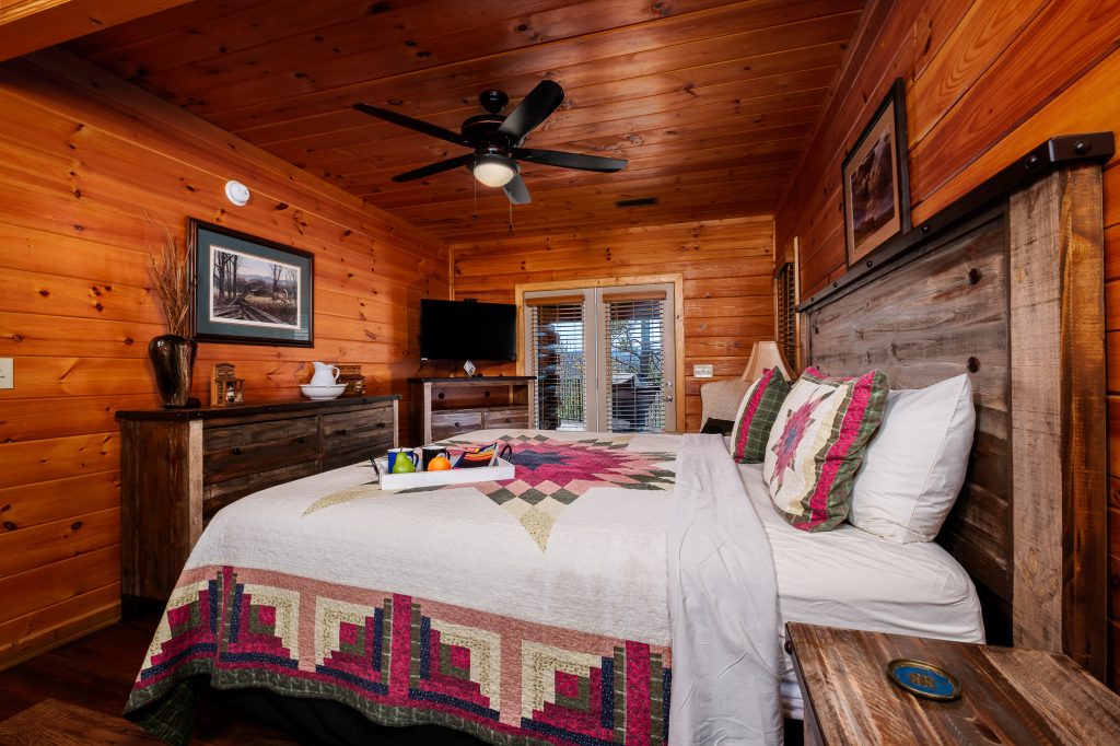 Wood-paneled king bedroom with quilt at a vacation rental in Gatlinburg, Tennessee.
